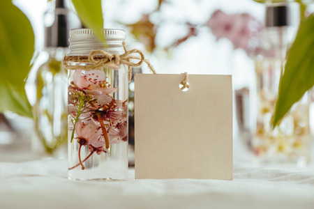 Essential oil, empty tags and fresh almond flowers, on green leaves backgroundの写真素材
