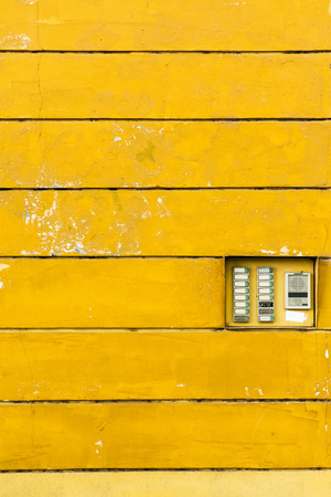 Retro doorbell: electric intercom on te yellow wall texture. Negative spaceの写真素材