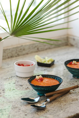 Spanish Gazpacho cold vegetable soup made of tomato, cucumber, bell pepper, onion, garlic and olive oil served in ceramic bowl .の写真素材