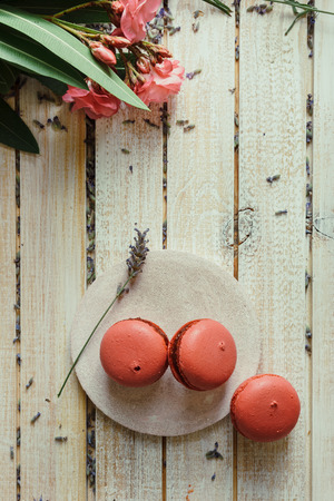 Pink macaroons, peach and lavender flavor, on light wood table and decorated with natural flowersの写真素材