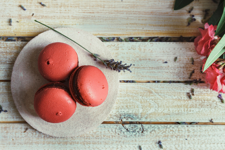 Pink macaroons, peach and lavender flavor, on light wood table and decorated with natural flowersの写真素材