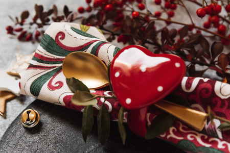 Holiday table setting, black plate with red heart-shaped napkin holder, on rustic textureの写真素材