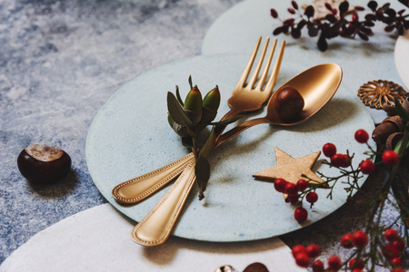 Christmas table setting, golden cutlery and nandinas, on grunge table. Holiday dinnerの写真素材