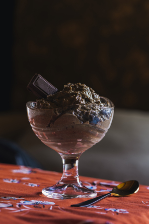 Chocolate mousse in glass cup, on orange flower tableclothの写真素材
