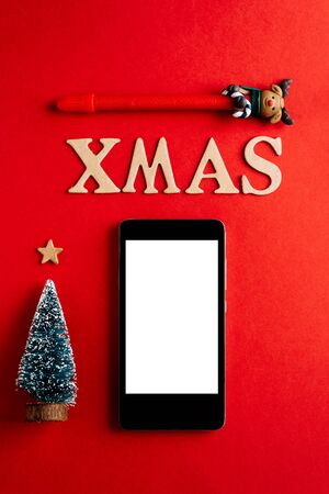Christmas empty mobile phone on red background, Holiday planning and xmas ornamentの写真素材