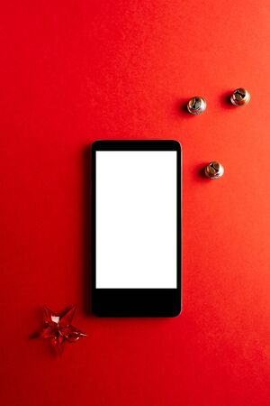 Christmas empty mobile phone on red background, Holiday planning and jingle bells decoration.の写真素材