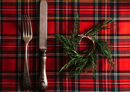 Vintage cutlery with small pine wreath on red checkered cloth, festive Menu. Christmas or thanksgiving backgroundの写真素材