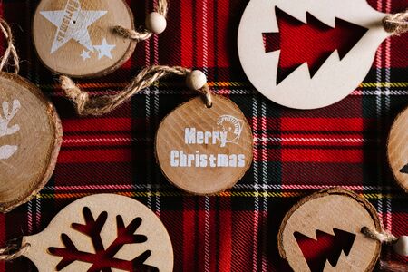 Modern wooden ornaments with a Christmas message for decoration, on a red tartan background. Christmas backgroundの写真素材