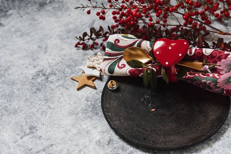 Holiday table setting, black plate with red heart-shaped napkin holder, on rustic textureの写真素材