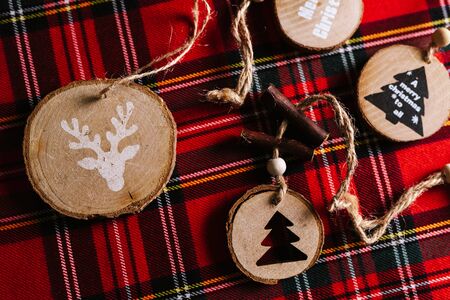 Modern wooden ornaments with a Christmas message for decoration, on a red tartan background. Christmas backgroundの写真素材