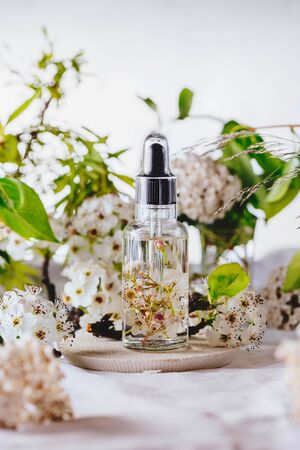 Essential oil, with fresh white flowers of cherry, on green leaves backgroundの写真素材