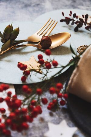 christmas table setting, golden cutlery and nandinas, on grunge table. Holiday dinnerの写真素材