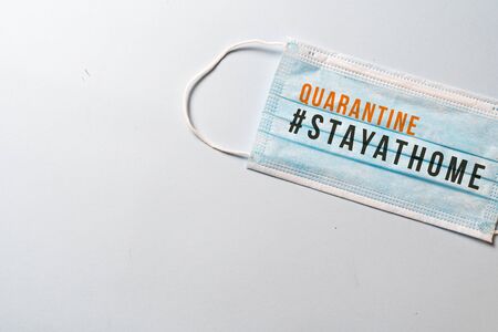 #STAYATHOME. surgical mask with showing the message "STAY AT HOME-QUATANTINE"., COVID-19,Virus prevention and quarantine minimal concept. White backgroundの写真素材