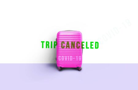 Pink suitcase standing next to wall with message. Stop travel to risk places COVID-19. prevention of contagion. Coronavirus crisis in travel and tourism industry conceptの写真素材