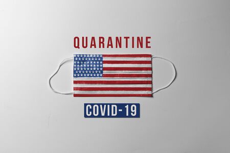 Covid-19. Surgical mask with the United States flag showing the message "QUARANTINE" due to global spread of Coronavirus. concept of quarantine at home as preventative measure against coronavirus outbreak.の写真素材