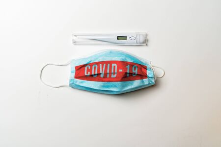 Covid-19. digital thermometer and Surgical mask showing the message