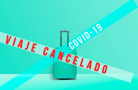 Soft blue suitcase standing next to wall with message. Stop travel to risk places COVID-19. prevention of contagion. Coronavirus crisis in travel and tourism industry conceptの写真素材