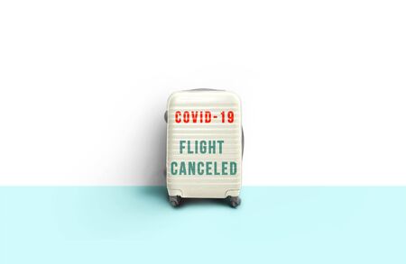 White minimal suitcase standing next to wall with message "flight candeled". Stop travel to risk places COVID-19. prevention of contagion. Coronavirus crisis in travel and tourism industry conceptの写真素材