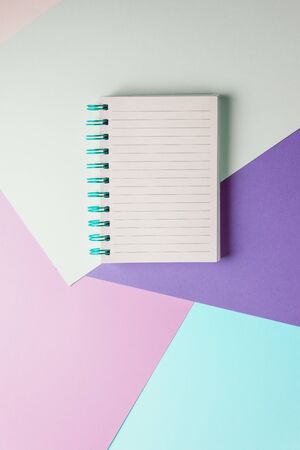 notebook with blank sheet and blue spiral on a colorful pastel background.の写真素材
