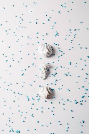 sea shell and seahorse in white color surrounded by small turquoise blue stones on bright background, Summer concept.の写真素材