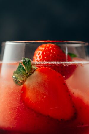 Delicious strawberry cocktail. Fresh summer cocktail with natural strawberry and ice cubes. Glass of strawberry soda drink on grunge dark background. Detail front viewの写真素材