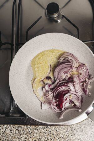 skillet with chopped red onion and butter on the kitchen fireの写真素材