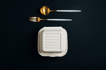 Healthy food concept: white burguer packaging closed with golden fork and spoonの写真素材