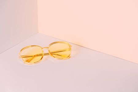 Modern yellow sunglasses in front of the corner of the wall background with copy space. Product photograph of minimalist concept with room for text, front viewの写真素材