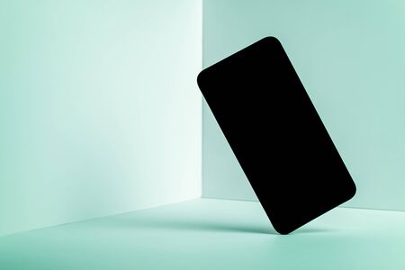 Minimalist modern smartphone mockup for presentation, in perspective front of the corner angle of the wall, with overlapping shadows on green background. application display, information or graphicsの写真素材