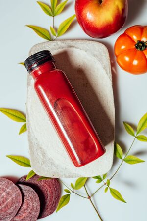 Red smoothie drink in bottle near ripe apples tomatoes and beets. Detox diet for healthy body and mind. health food concept. On light backgroundの写真素材