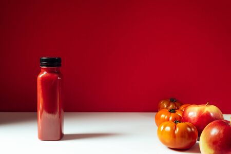 Red smoothie drink in bottle near ripe apples and tomatoes  Detox diet for healthy body and mind. health food concept. Front viewの写真素材