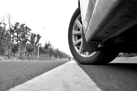 Ultra low angle shot on the road in front of the car on the front wheelのeditorial素材