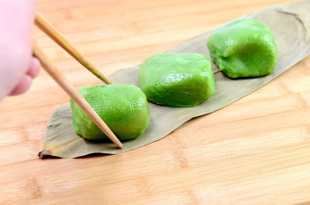 Person picking up green dumpling with chopstick (Qingming festival traditional cuisine)の写真素材