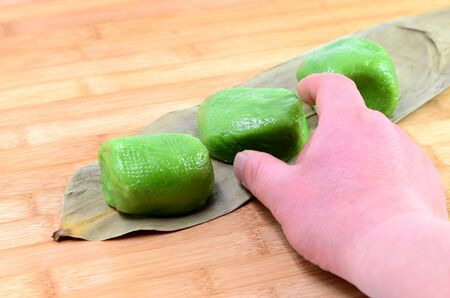 Person reaching towards delicious green dumplingの写真素材