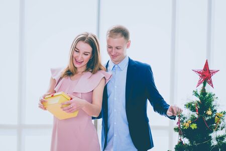 A young woman in the pink dress and a young man in the suit and jeans with merry Christmas, Happy...