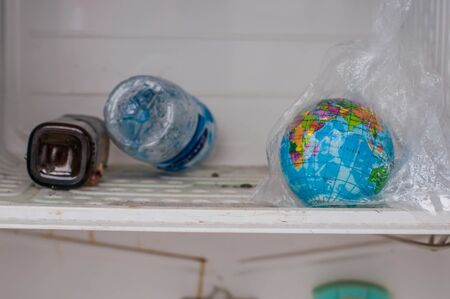 A globe, waste, and plastics in an old refrigerator.の写真素材