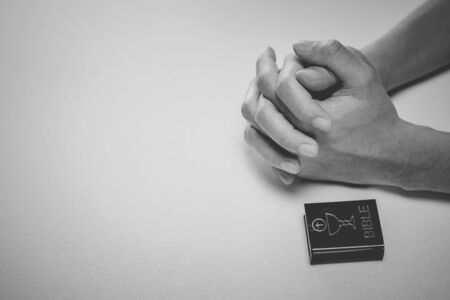 A woman is praying by her hands and white - black tone. Praying hands and bible.の写真素材