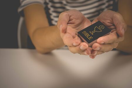 A woman is praying by her hands. Praying hands and bible.