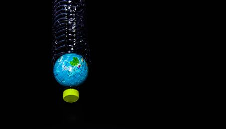 A globe in a plastic bottle on black background, which is concept of global environment from...