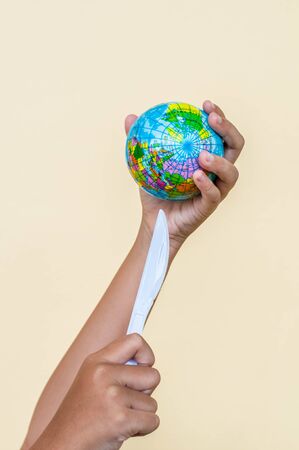 Plastic steak knife is destroying the globe, which is concept of global environment from plastic.の写真素材