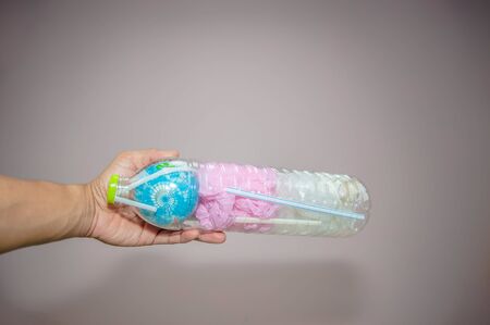 Hand hold a globe, plastic bags and plastic tubes in plastic bottle, which is concept of global...