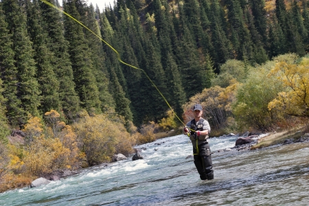 fly fishing angler makes cast while standing in waterの写真素材