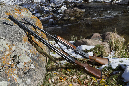 Two guns lying on a rock on a background of autumn landscapeの写真素材