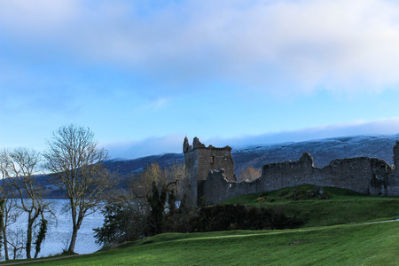 Snowy winter's view of Urquhart Castle with barren trees and Loch Ness in the background.のeditorial素材