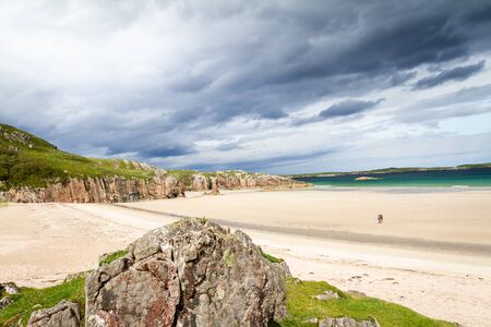 Beautiful view after a storm of Ceannabeine Beach with a couple walking together in the distance in Northern Scotlandの写真素材