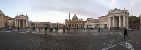VATICAN - OCTOBER 12, 2015: Panorama view of the front of Saint Peter Square and Saint Peter's Basilica in the evening with tourists walking aroundのeditorial素材