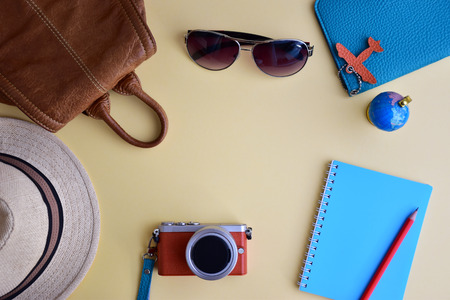 Traveler's accessories for trip planning  flay lay on light yellow background with brown leather...