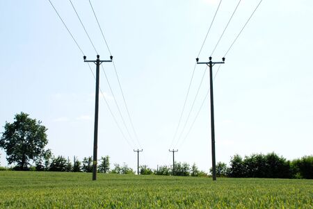Electricity pylons carrying power above a farm field, contrasting technology and agriculture