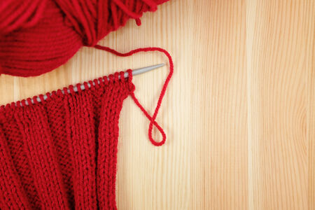 Red rib stitch on the knitting needle with a ball of wool, on woodの写真素材