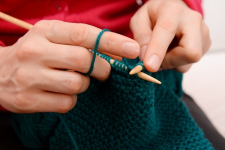 Closeup of woman knitting with teal yarn